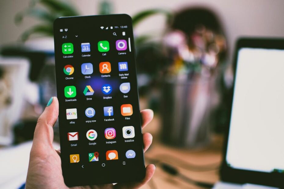 Mobilny telefon na stole, z widoczną aplikacją do wiadomości otwartą na ekranie.